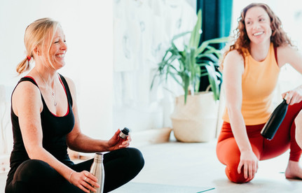 Yoga students laugh together in bright studio